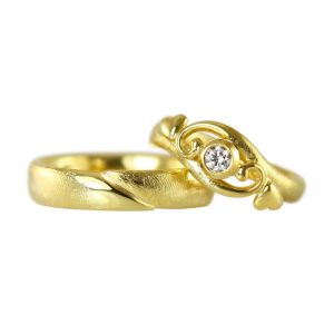 Romantic gold wedding ring with heart and scrolls embracing a white diamond