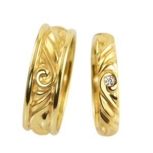Soft undulating wedding rings with polished surface and a white diamond