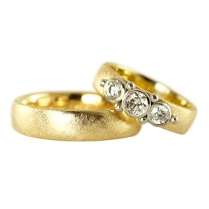 Heavy gold wedding rings where her symmetrical bubble ring is set with 3 large diamonds