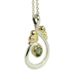 Beautiful curl pendant in silver with gold details and a large green sapphire.