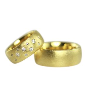 Wide gold wedding rings with a matte finish and a sprinkling of small diamonds