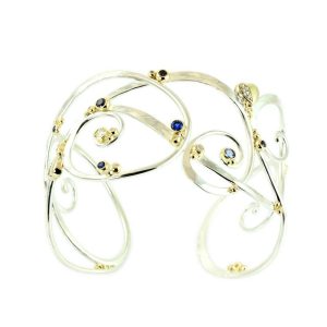 Unique curl bracelet in white gold with gold bubbles and coloured sapphire.