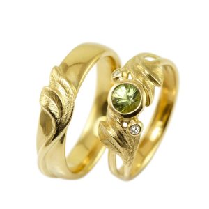 Wedding rings with twirling leaves in gold with large green sapphire and small white diamonds