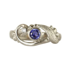 Asymetric scroll and leaf ring in silver with small white diamond and large blue sapphire