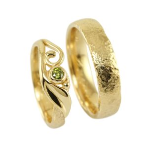 Wedding rings in gold scroll and green diamond. His ring with rough polished surface